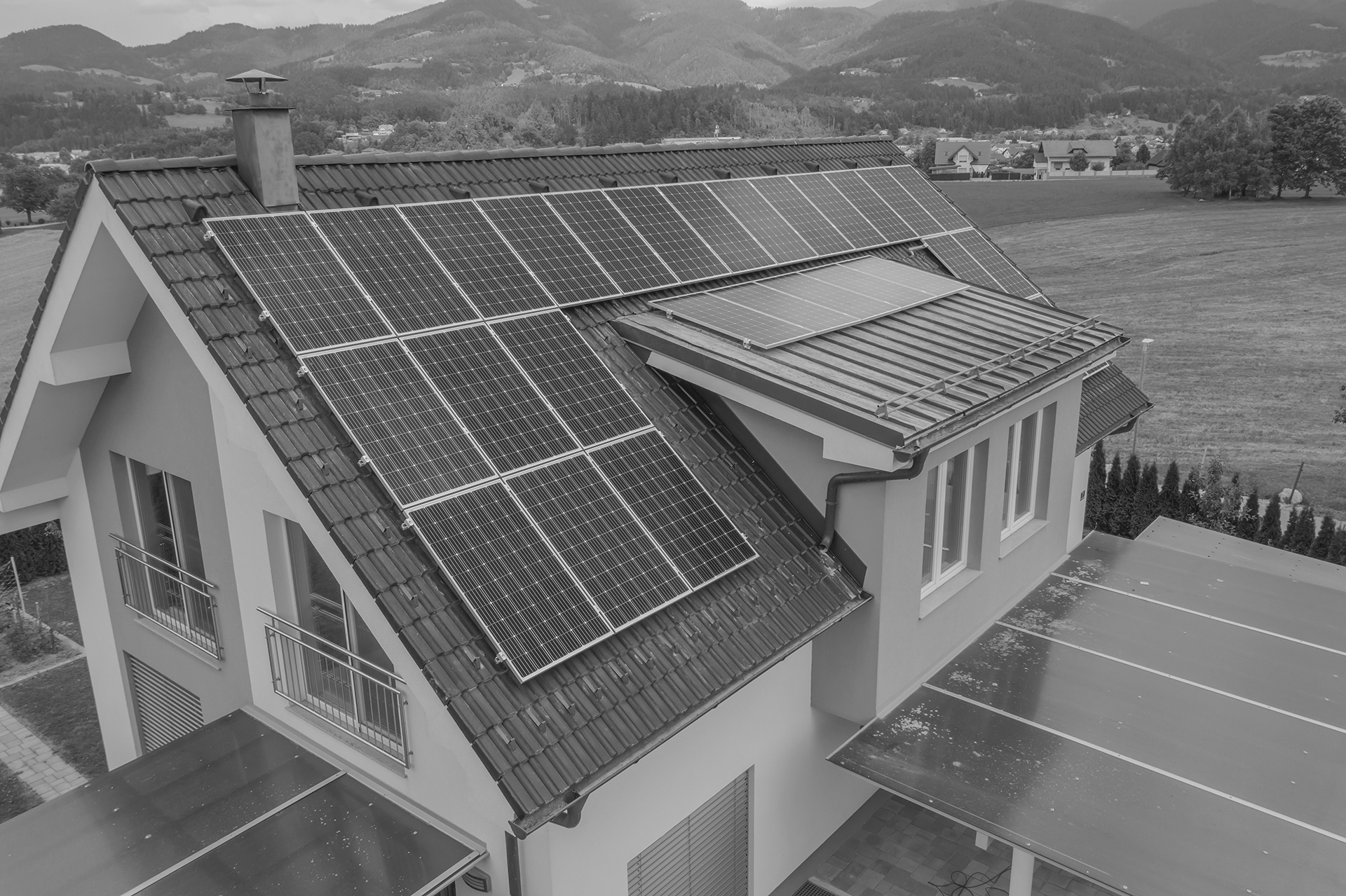 A high angle shot of a private house situated in a valley with solar panels on the roof